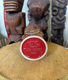 Bottom view of a slipcase brown ceramic tiki mug with a detailed face, green leaves, and gold accents.